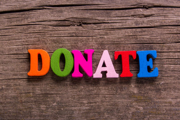 Fototapeta premium donate word made from colored wooden letters on an old table. Concept