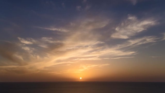 4k time lapse of clouds crossing the amazing sky over the sea or ocean at sunset. transition from day to night. The clouds cross slowly from left to right colored yellow orange purple blue