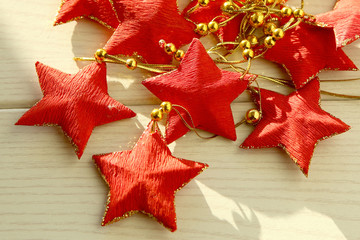 Red five-pointed stars garland. Decoration with stars on white wooden surface.