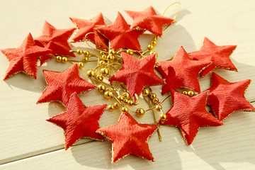 Red five-pointed stars garland. Decoration with stars on white wooden surface.