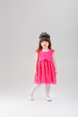 beautiful little girl in pink Princess dress with crown on gray 