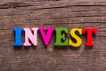 invest word made from colored wooden letters on an old table. Concept