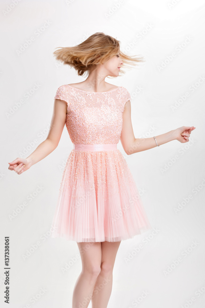 Wall mural beautiful blond woman in a pink cocktail dress dancing and havin