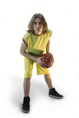 Young boy with long blond hair wearing a green jersey in a squatting position holding a basketball