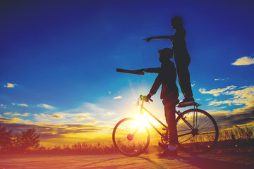 Fototapeta na wymiar Silhouettes couples and bicycle on sunset sky,couples concept .