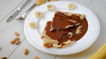 Pancakes with bananas and chocolate served on a plate