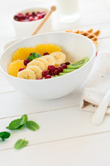 Healthy breakfast: fresh cottage cheese with orange,banana, kiwi, cranberry and honey on white wooden table. Selective focus