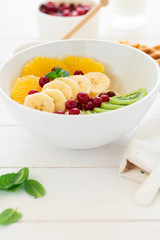 Healthy breakfast: fresh cottage cheese with orange,banana, kiwi, cranberry and honey on white wooden table. Selective focus