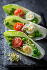 Extraordinary salad in chicory with quail egg, tomato and avocado