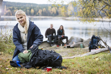 Young Woman Unpacking Backpack At Campsite