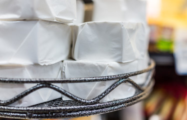 Many packages of brie wrapped in white paper on display