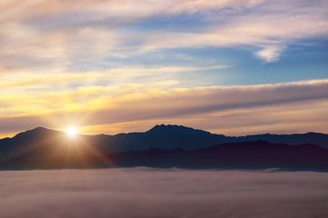 Fototapeta na wymiar Bright sunrise, the mist in a mountain valley and mountain peaks on the horizon.