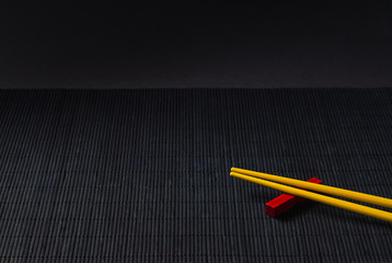 Sushi chopsticks on black bamboo straw mat