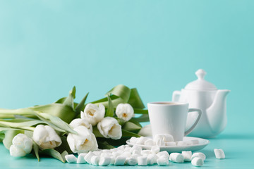 Obraz na płótnie Canvas Breakfast with coffee cup and white tulips on plain background
