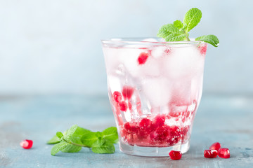 Infused water made of fresh pomegranate and mineral water with ice, cold refreshing and detox drink
