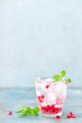 Infused water made of fresh pomegranate and mineral water with ice, cold refreshing and detox drink