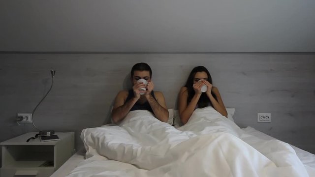 Couple in bed with cups. People talking and smiling. Have a chat with beloved. You impress me every day.