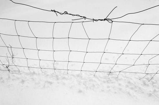 Wire netting and snow as simple and clean minimalist abstract composition - silhouette of dark lines on white and bright background 