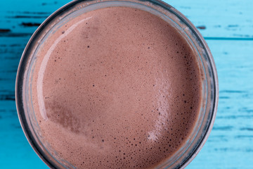 Top view of chocolate milkshake on blue wooden table