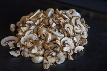 champignon mushrooms raw sliced slices on a table on a black background