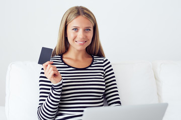 Young smiling woman doing online shopping with laptop at home in the living room