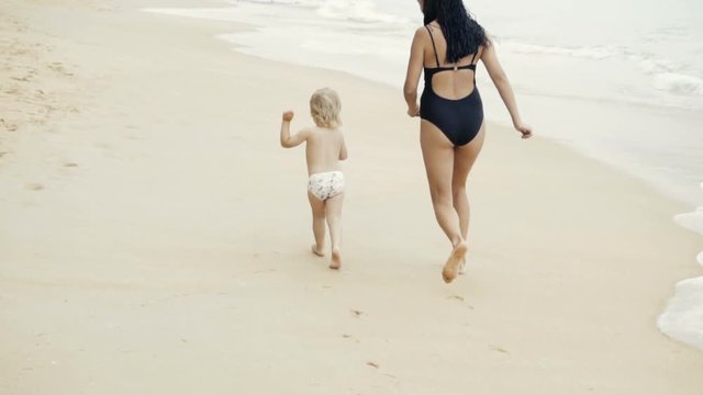 Mother and daughter are running on the beach
