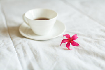 cup of tea and flower on white bed