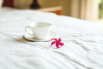 cup of tea and flower on white bed