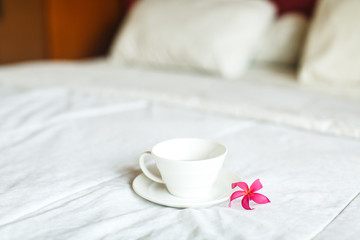 cup of tea and flower on white bed