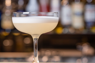 Cocktail in Margarita glass, pale dogwood pink color, with foam on top, selective focus