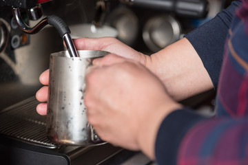 Barrista frothing milk for cappuccino, selective focus