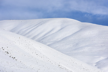 Fototapeta na wymiar Snow Covered Hills with Blue Sky