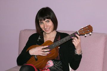Fototapeta premium Giovane donna sorridente suona l'ukulele 