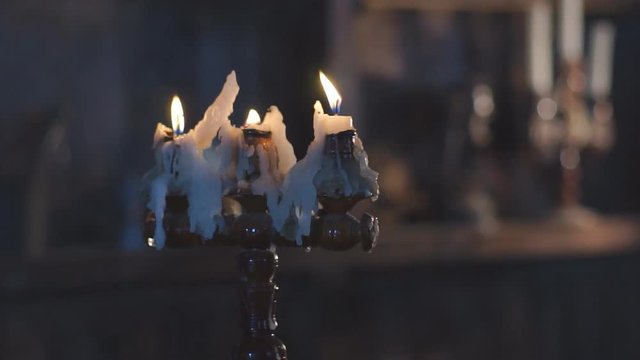 Three wax candles burning in candlestick Burning candle wax, melted wax slowly runs down to the bottom of the stand