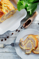 charcuterie, meat, baked chicken roll with egg omelette, peppers, herbs and salad leaves on a white wooden background 