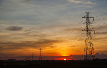 Fototapeta na wymiar Sunset against high electric voltage pole landscape