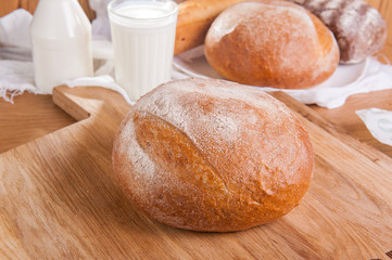 Close up traditional rye bread on the background of assortment of breads and glass of milk. Selective focus