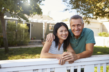Portrait Of Mature Couple Looking Over Back Yard Fence