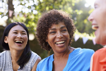 Mature Female Friends Socializing In Backyard Together