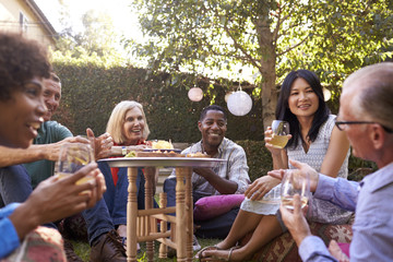 Group Of Mature Friends Enjoying Drinks In Backyard Together