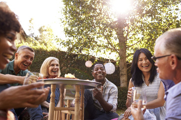 Group Of Mature Friends Enjoying Drinks In Backyard Together
