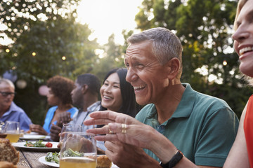 Group Of Mature Friends Enjoying Outdoor Meal In Backyard
