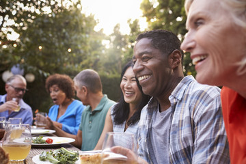 Group Of Mature Friends Enjoying Outdoor Meal In Backyard