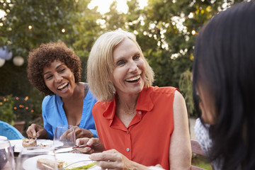 Mature Female Friends Enjoying Outdoor Meal In Backyard