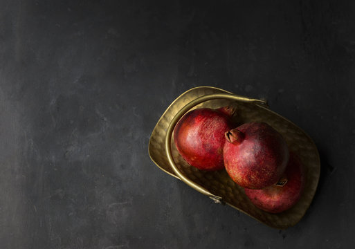 Pomegranates in golden metal trug