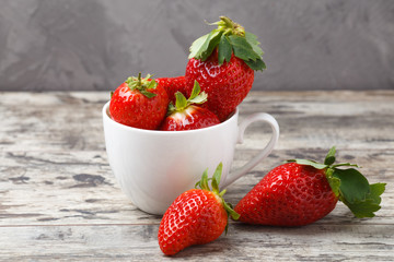 fresh strawberries in a white cup on wooden background
