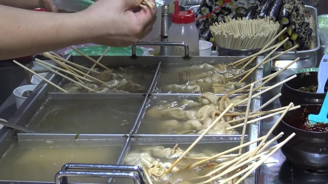 Korean Street Foods a variety of oden ingredients, people eating the fish cakes and other snack-Dan