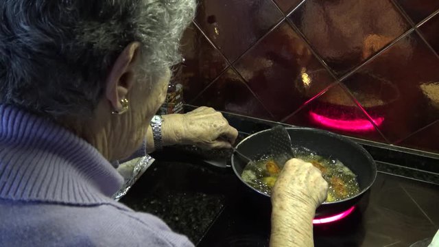 4k, Spanish Grandmather is cooking a cylindrical croquettes in hot pan with olive oil of a kichen. Croquette is a small breadcrumbed fried food roll containing main ingredients ground meat -Dan