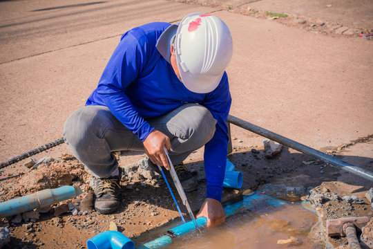 Construction worker,Repairing a broken water pipe on the concrete road.