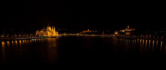 Fototapeta na wymiar Panoramic night view on Hungarian Parliament Building located at the bank of the Dunabe river in Budapest, Hungary